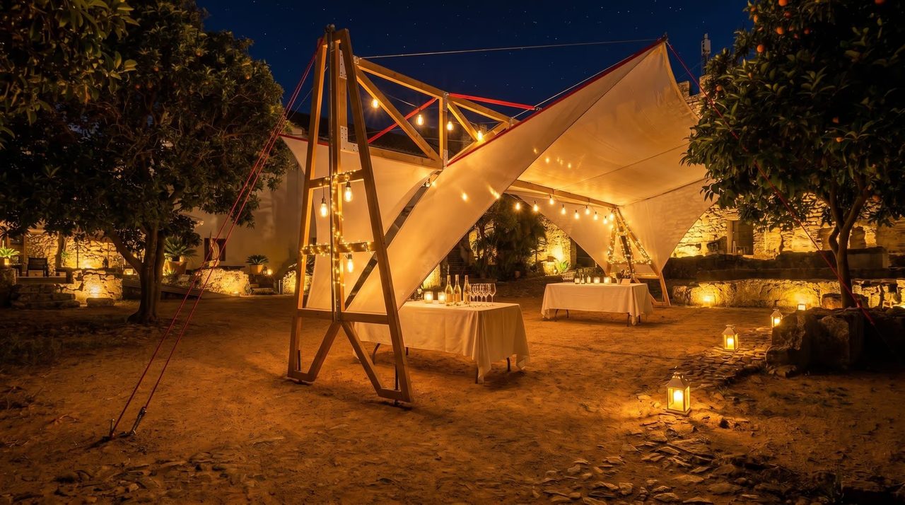 Carpa para evento nocturno con iluminación cálida en patio de hotel
